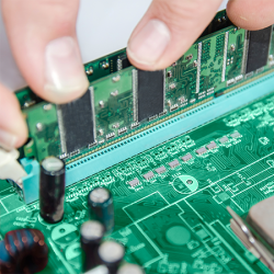 Hands placing a memory card into a slot on a circuit board